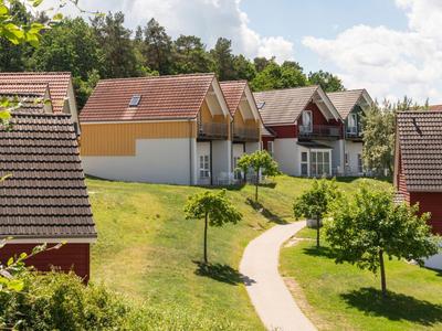 Row of modern holiday homes with manicured lawns and a pathway in green surroundings