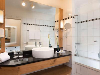 Modernes Badezimmer mit Waschbecken, Spiegel, Handtüchern und Badewanne mit Dusche.