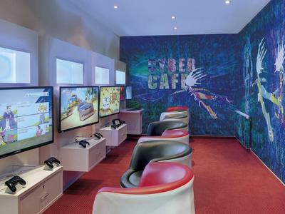 Modern gaming area with chairs, screens, and cyber-themed wall indoors.