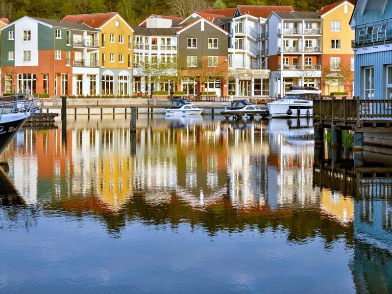 Colorful houses by calm water with boats and harbor scene in clear weather
