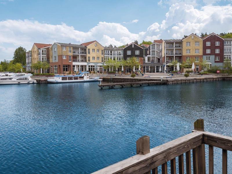 View of a harbor with colorful houses and boats under a clear sky.