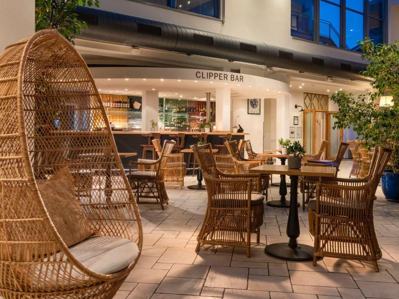 Cozy café outdoor area with rattan chairs and a large hanging basket.