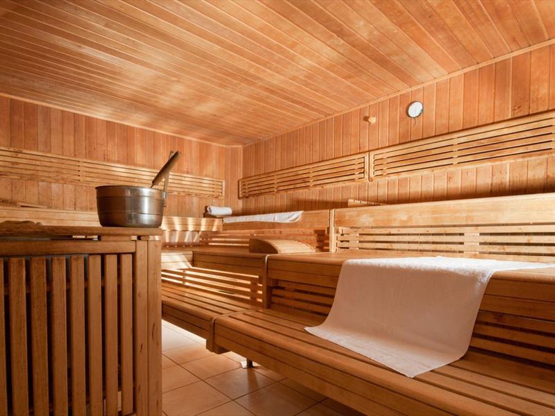 Wooden sauna with multi-level benches and a sauna bucket
