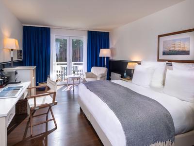 Hotelzimmer mit großem Bett, Schreibtisch, Dekoration und Balkon mit Blick nach draußen.