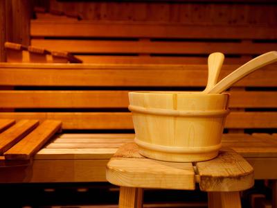 Holzsauna mit einem Holzeimer und einer Kelle auf einem kleinen Hocker.