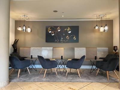 Moderner Hotel-Loungebereich mit Stühlen und Wandkunst in beruhigenden Farben.