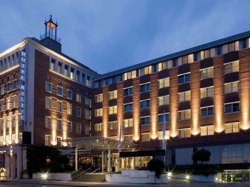 Oświetlony wielopiętrowy budynek hotelu o zmierzchu z bezchmurnym niebem.