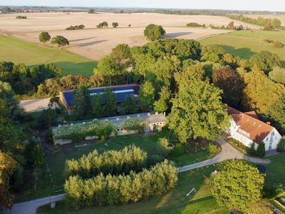 Luchtfoto van een hotel omgeven door bomen en velden met duidelijke paden en groene gazons.