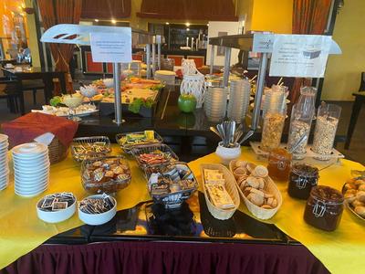 Buffet with pastries, cereals, and breakfast items on a yellow table in the breakfast room.