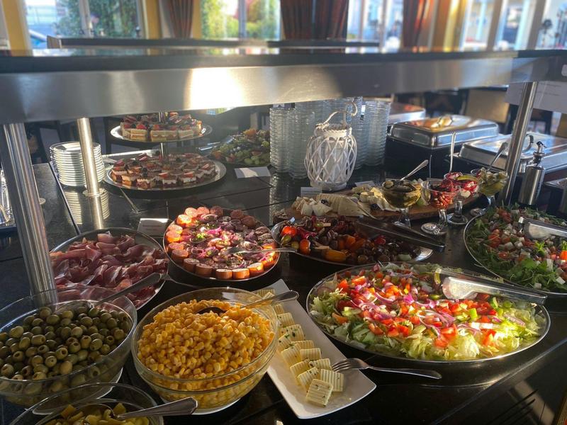 Buffet with a variety of salads, cheese, olives, and other appetizers in a hotel kitchen.