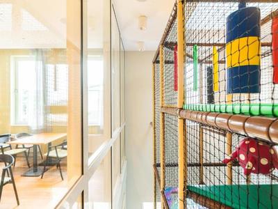 Pohled na barevné vnitřní hřiště vedle třídy se stoly a židlemi.