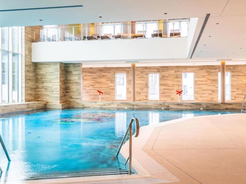 Světelný krytý bazén s velkým oknem a moderní atmosférou v hotelovém spa.