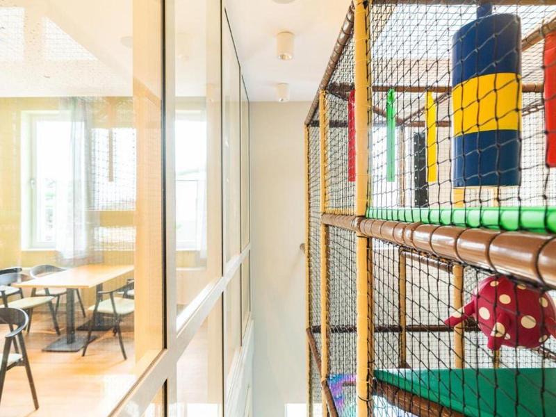 Pohled na barevné vnitřní hřiště vedle třídy se stoly a židlemi.