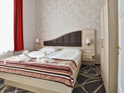 Une chambre d'hôtel simplement meublée avec un lit double, une couverture rayée et deux serviettes.