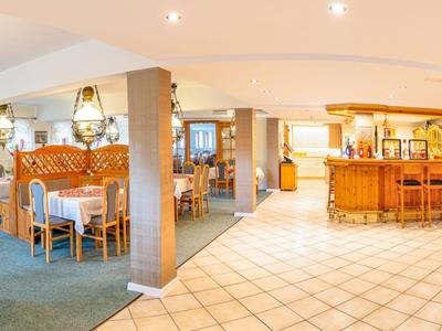 Bright spacious restaurant area with set tables and a bar in a hotel.