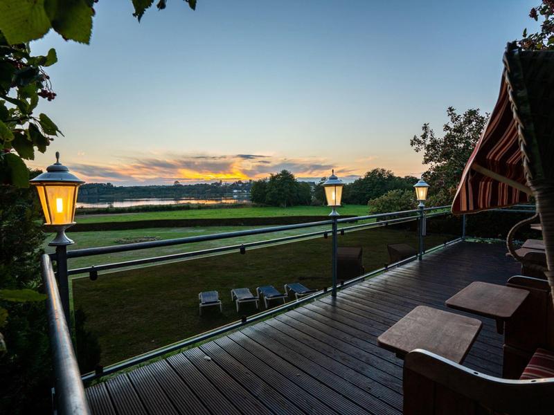 Wooden balcony with lanterns overlooking a lake at sunset