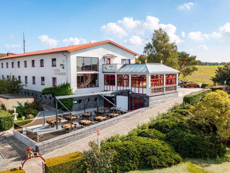 A hotel building with an outdoor seating area in a rural setting under a blue sky.
