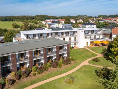 Complesso alberghiero moderno con due edifici circondati da prati e sentieri.