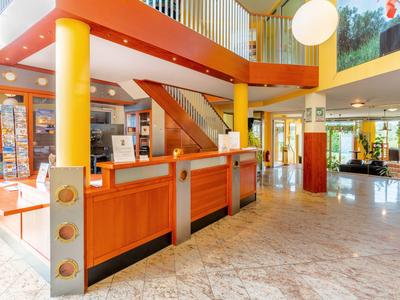 Heller Hotel-Empfangsbereich mit Holztheke und modernem Design.