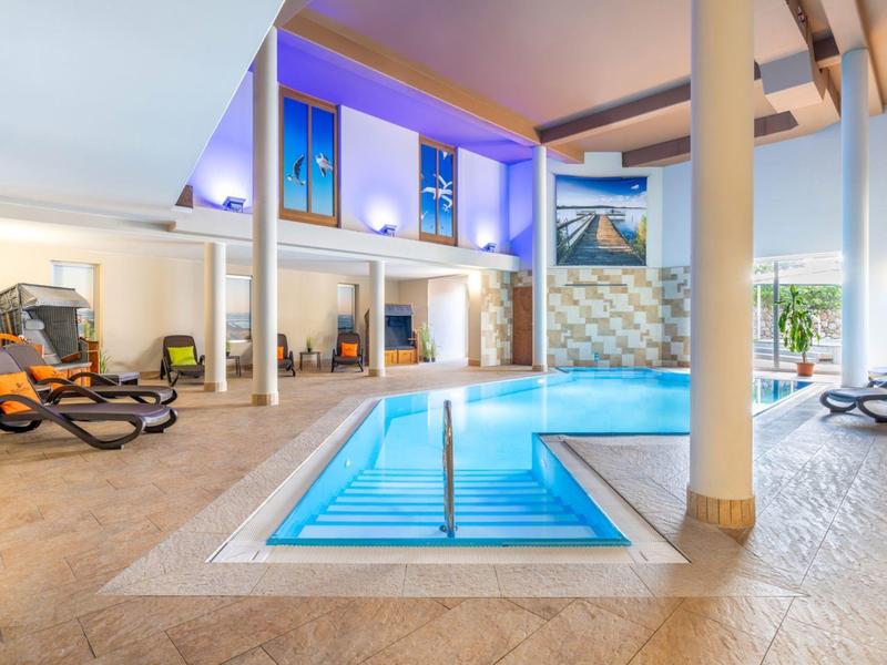 Moderner Indoor-Poolbereich mit Liegestühlen und großen Fenstern in einem Hotel.