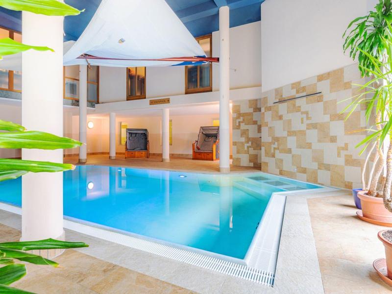 Innenpoolbereich mit blauem Wasser, Pflanzen und moderner Architektur in einem Hotel.