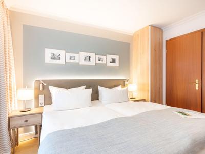 Chambre d'hôtel lumineuse avec lit double confortable, tables de chevet et éclairage moderne.