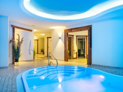 Bain à remous moderne dans un espace bien-être bien éclairé avec éclairage bleu au plafond.