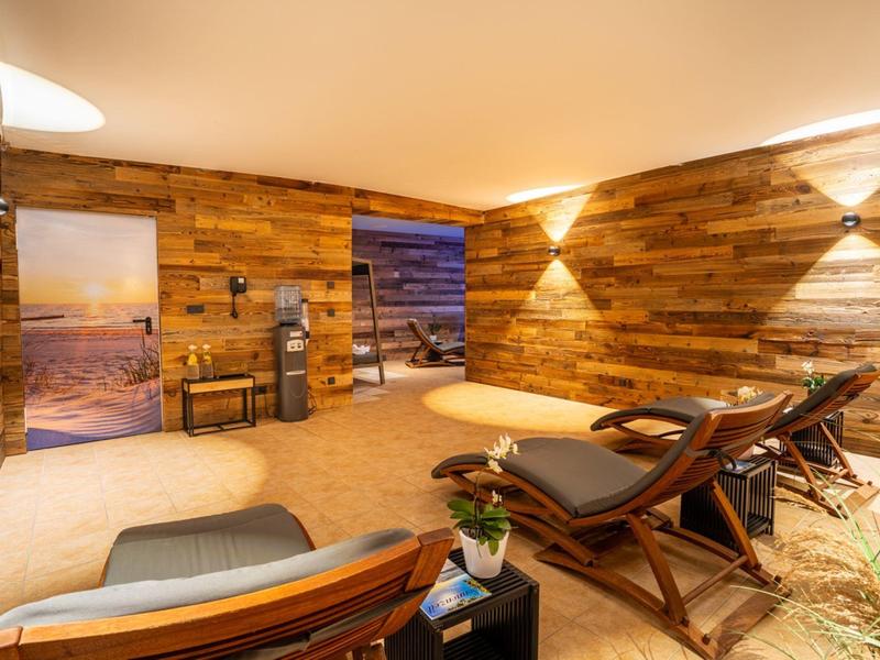 Cozy spa room with wooden paneling, loungers, and calming lighting.