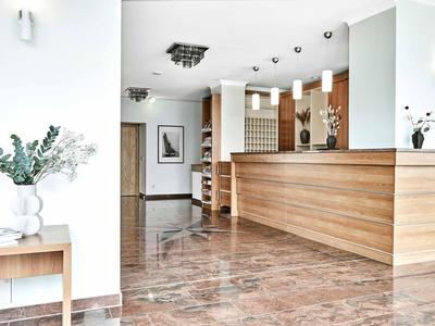 Reception di hotel luminosa con bancone in legno e pavimento in marmo