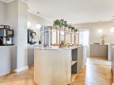 Jasna jadalnia śniadaniowa z wyspą bufetową i ekspresami do kawy w nowoczesnym stylu.