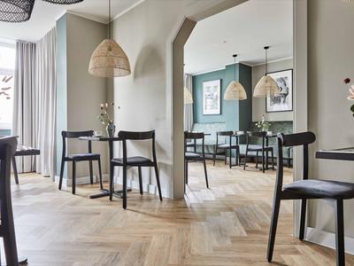 Nowoczesna strefa wypoczynkowa w hotelu z drewnianymi krzesłami, lustrem i naturalnym światłem