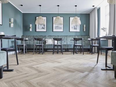 Nowoczesna jadalnia z drewnianymi krzesłami, stołami i zielonymi ścianami w restauracji hotelowej.