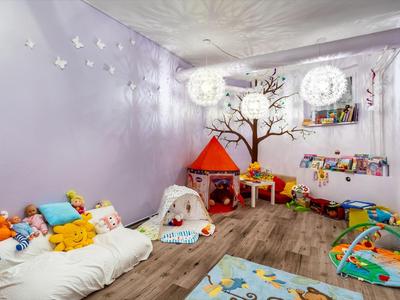 Colorata stanza giochi per bambini con giocattoli, tenda e posti a sedere morbidi in una stanza luminosa.