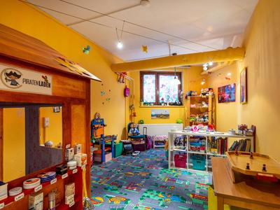 Stanza giochi colorata e accogliente per bambini con angolo cucina e scaffali per giocattoli.