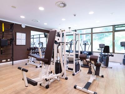 Attrezzature da palestra moderne in una stanza luminosa con grandi finestre.