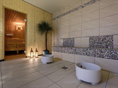 Modern sauna area with heated stone bench, plants, and atmospheric lighting.