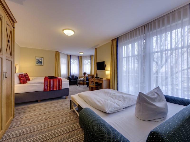 Bright hotel room with large window, seating area, and double bed.