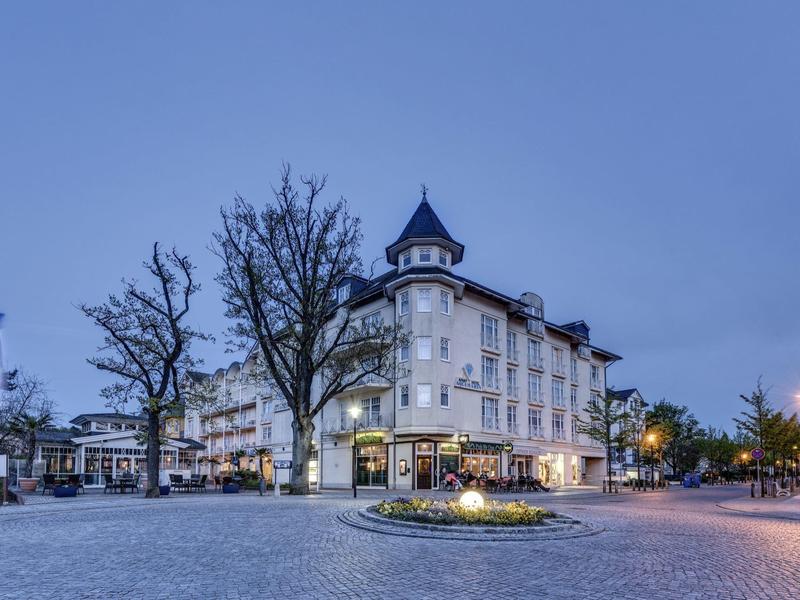 Historic hotel building in city center at dusk with illuminated windows.