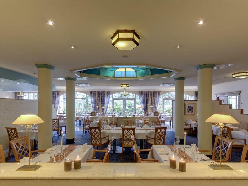 Elegant hotel restaurant with set tables and warm lighting.