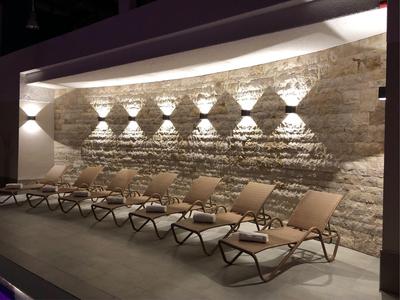 Řada pohodlných lehátek před osvětlenou kamennou zdí v klidné venkovní oblasti.