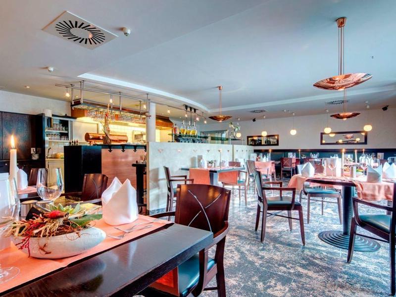 Světla restaurace s velkými okny, moderním nábytkem a útulnou atmosférou.