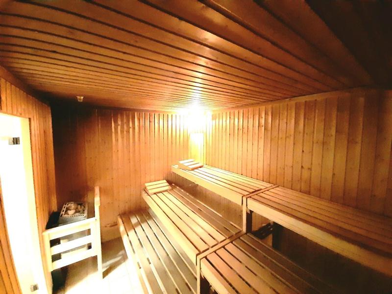 Holzsauna mit mehrstufigen Holzliegen und warmem gelbem Licht an der Decke.