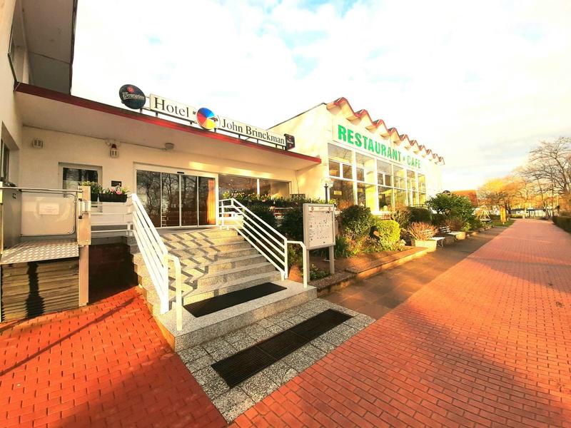 Außenansicht eines Restaurants mit Treppe, großem Eingangsbereich und rotem Pflasterweg.