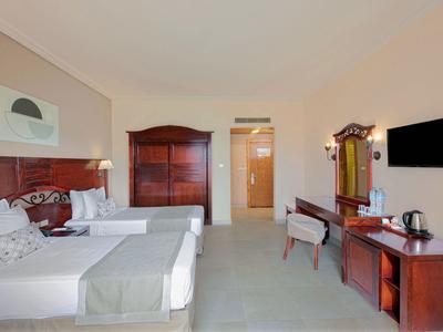 Hotelzimmer mit zwei Einzelbetten, Holzmöbeln und einem Flachbildfernseher an der Wand.