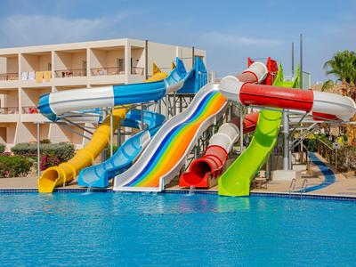 Mehrere bunte Wasserrutschen führen in einen großen Pool vor einem Hotelgebäude.