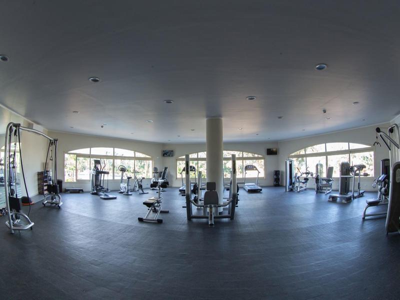 Spacious, well-lit gym with various exercise equipment and large windows overlooking outdoors.