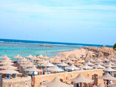 Viele Stroh-Sonnenschirme am Strand mit Blick auf das blaue Meer und den Himmel.