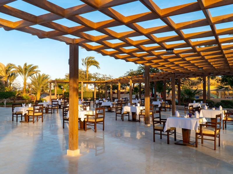 Large covered outdoor seating area with tables and chairs at a hotel.