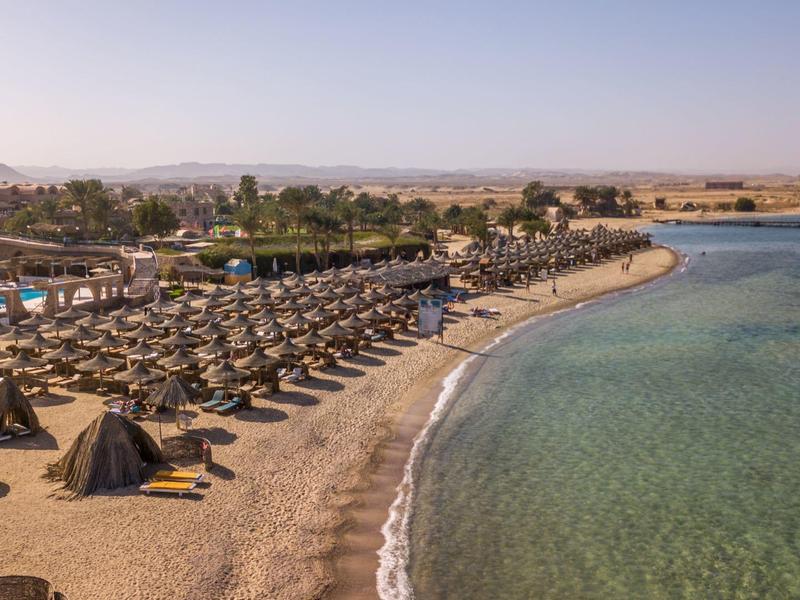 Beach with loungers and umbrellas beside clear water on a sunny day