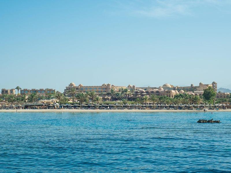 Large hotel by the beach with clear sky and calm sea in the foreground.